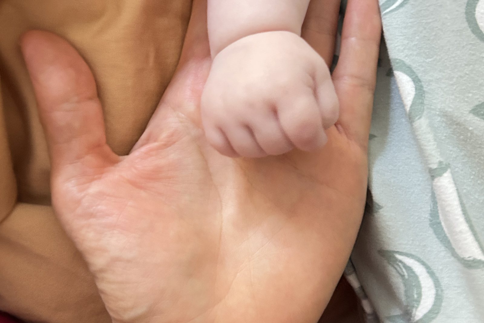 A baby's hand resting in Caiyun Xu's palm